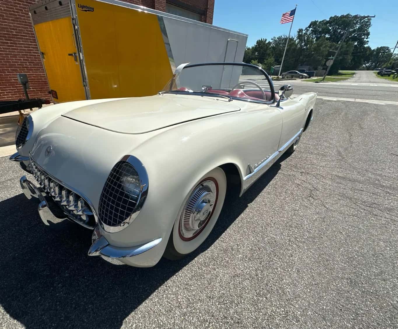White 1950s Corvette roadster beside an enclosed trailer