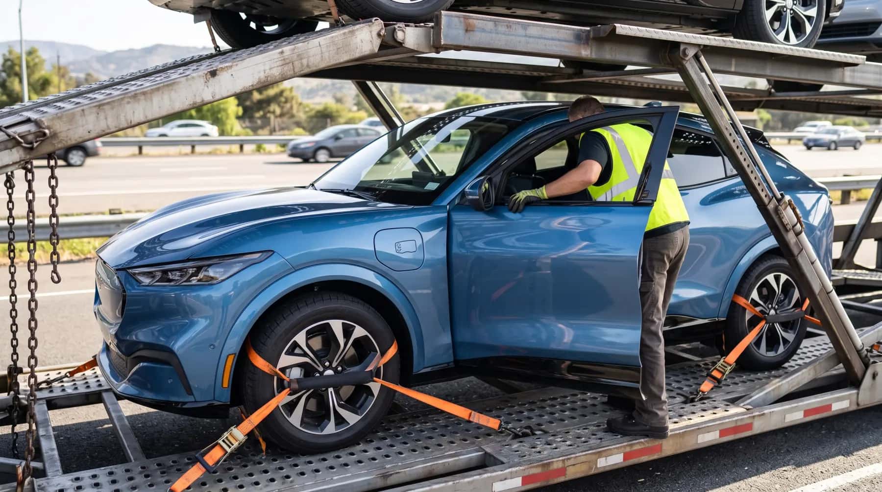 Driver strapping an electric SUV onto a carrier deck