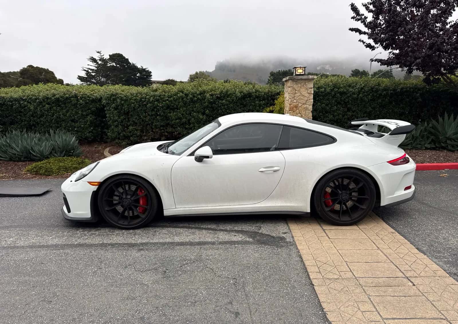 White Porsche 911 GT3 at delivery, fog on the hills behind